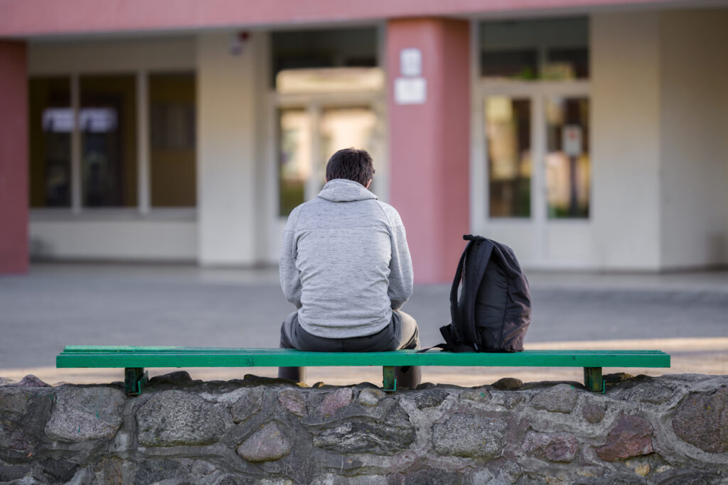 Boy sat on bench outside school